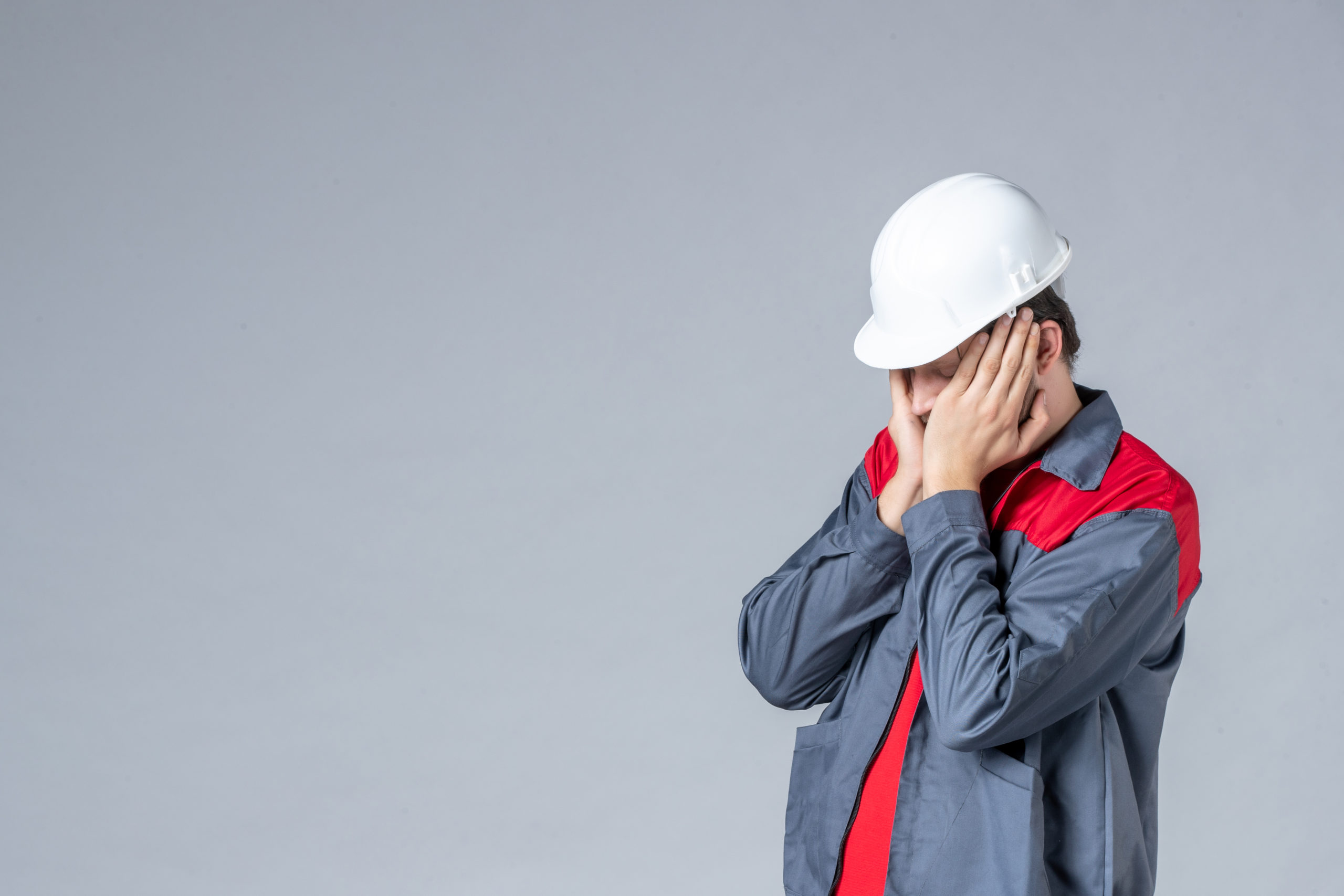 front view male builder in uniform and helmet stressed on gray background